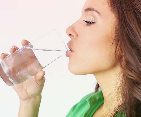 Mujer bebiendo vaso de agua uno de los Métodos para adelgazar